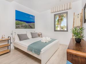 a white bedroom with a bed and a window at Playa de Muro Chalet with Pool for 6 in Playa de Muro +17 photos