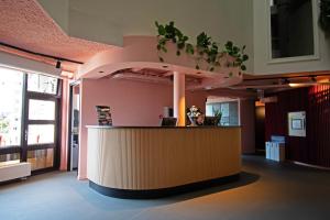 a lobby with a counter with plants on the wall at Stayokay Hostel Rotterdam - fully renovated April 2026 in Rotterdam