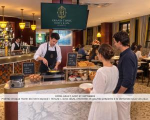 a man preparing food at a counter in a restaurant at Grand Tonic Hotel & SPA NUXE in Biarritz +54 photos