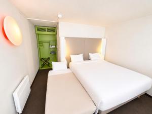 two beds in a small room with a green door at Campanile Troyes Sud - Buchères in Troyes
