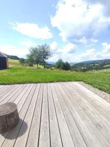a wooden deck with a tree stump on a field at Domek Fika in Laskowa +3 photos