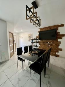 a dining room with a table and chairs and a television at Le Gustave - Proche ville in La Rochelle