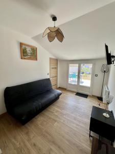 a black couch in a living room with a ceiling fan at Le Gustave - Proche ville in La Rochelle