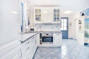 a white kitchen with white cabinets and appliances at Ferienhaus-Seehund in Glowe