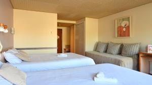 a hotel room with two beds and a couch at Logis Hôtel & Restaurant Le Cheval Blanc et Clovis in Vouillé