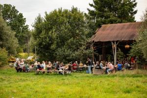 a group of people sitting at tables in a field at Strackxhoeve Tiny House 'Knalselder' in Laakdal +14 photos
