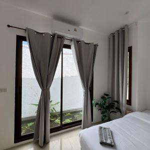 a bedroom with a bed and a large window at Glory Moon Resort in Bophut
