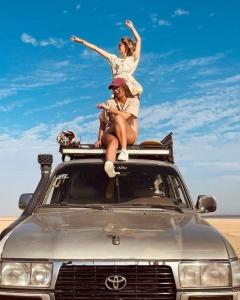 two women sitting on the roof of a car at Fayoum Safari Camp in Qaryat at Ta‘mīr as Siyāḩīyah