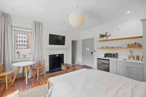 a white bedroom with a bed and a table and a kitchen at Suite 4C at Maison Dupont a Dupont Circle Inn in Washington, D.C.