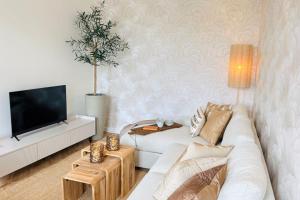 a living room with a white couch and a tv at Cooth's Prestige at the Square in Breda