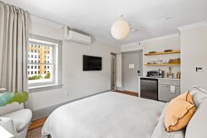 a bedroom with a white bed and a kitchen at Suite 5C at Maison Dupont a Dupont Circle Inn in Washington, D.C.