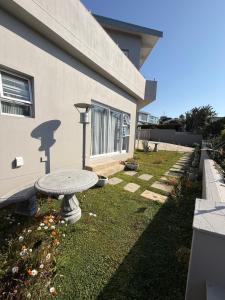 a garden with a table in front of a house at Berg & Baai guesthouse in Plettenberg Bay