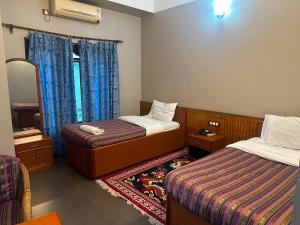 a hotel room with two beds and a mirror at Hotel Pelri in Phuntsholing
