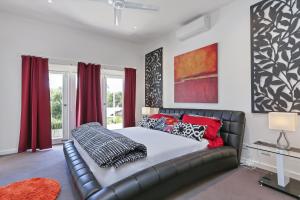 a bedroom with a leather couch and red curtains at Barossa White House The West Wing in Angaston