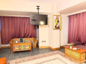 a living room with a tv on a wall with red curtains at Hotel Pelri in Phuntsholing