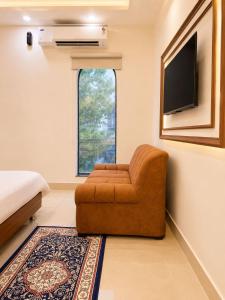 a living room with a chair and a tv at Megh hotel in Gangānagar