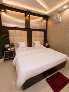 a bedroom with a large bed with white sheets at Megh hotel in Gangānagar +11 photos
