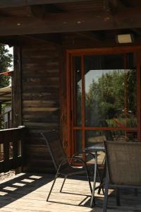 two chairs and a table on the porch of a cabin at Orr Halevana in Bruchim Qela' Alon