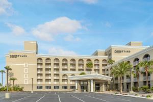 a large tan building with a parking lot at Courtyard by Marriott Jacksonville Beach Oceanfront in Jacksonville Beach