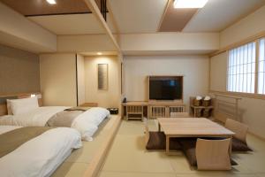 a room with two beds and a table and a tv at Onyado Nono Sakaiminato Natural Hot Spring in Sakaiminato