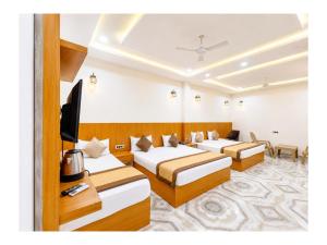 a hotel room with three beds and a flat screen tv at निर्मला पैलेस अयोध्या राम मंदिर - Hotel The New Nirmala Palace Ayodhya Near-Ram-Janmabhoomi-and-Ayodhya-Ram-Mandir-with-parking-and-Restaurant-Facilities - Best Hotel In Ayodhya in Ayodhya