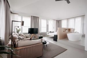 a living room with a couch and a bath tub at Strandhotel in Cadzand-Bad