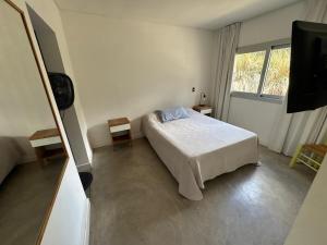 a white bedroom with a bed and a television at Casa Benito - Barrio Privado con Piscina en Chapadmalal in Mar del Plata +21 photos