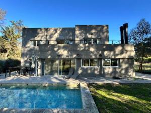 a house with a swimming pool in front of it at Casa Benito - Barrio Privado con Piscina en Chapadmalal in Mar del Plata
