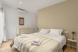 a white bedroom with a bed with towels on it at apt hospital in Tourrettes-sur-Loup