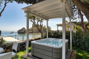 ein Whirlpool unter einer Pergola direkt am Meer in der Unterkunft La Plage Resort in Taormina