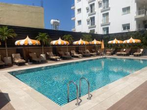 a swimming pool with chairs and umbrellas next to a building at La Terrazza Hotel in Famagusta