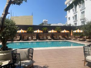 a swimming pool with chairs and umbrellas next to a building at La Terrazza Hotel in Famagusta