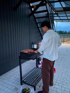 a man is cooking food on a grill at Барнхаус in Bosteri +1 photo