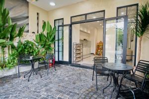 a patio with tables and chairs and plants at Maison Hin in Hoi An