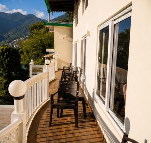 a row of chairs on the balcony of a house at The Oak Lake Cottage Boho in Nainital