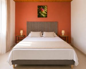 a bedroom with a large bed with an orange wall at La Kaz' Mathosie in Saint-André +2 photos
