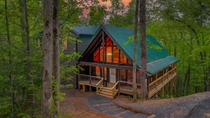 a log cabin with a green roof in the woods at Mountain Majesty By Ghosal Luxury Lodging in Gatlinburg