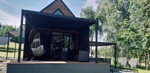 a small building with a black roof on a field at Zaciszna Idylla Domek z jacuzzi nad Jeziorem Złotnickim Karłowice in Olszyna