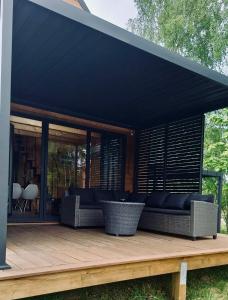 a house with a black roof on a wooden deck at Zaciszna Idylla Domek z jacuzzi nad Jeziorem Złotnickim Karłowice in Olszyna