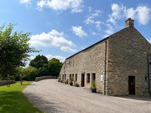 an old brick building with a gravel driveway at Howgills Barn in Sedbergh