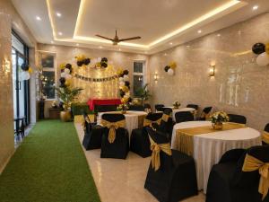 a banquet hall with white tables and black chairs at White Forest - PV Hotels in Pondicherry +170 photos