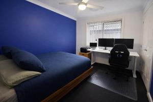 a bedroom with a bed and a desk with a computer at Maitland Getaway - Spa, EV Friendly, Pet Friendly in Telarah
