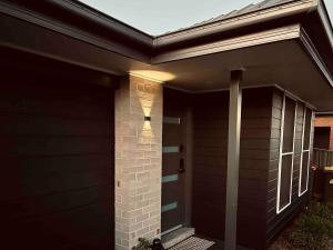 a black house with a door with a light on it at Maitland Getaway - Spa, EV Friendly, Pet Friendly in Telarah