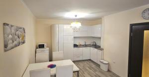 a small kitchen with white cabinets and a table and chairs at Sun Sea 3 sea view in Shkorpilovtsi