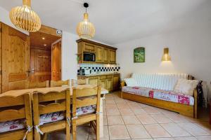 a bedroom with a bed and a kitchen with a table at Les Ancolies Benelli in Les Menuires