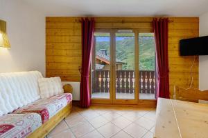 a room with a bed and a large window at Les Ancolies Benelli in Les Menuires