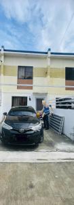 a man standing next to a black car parked in front of a house at Sta Cruz Laguna Transient House in Santa Cruz