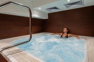 a woman is sitting in a hot tub at Urban Hotel & Spa Aix-les-Bains - BW Signature Collection in Aix-les-Bains +59 photos