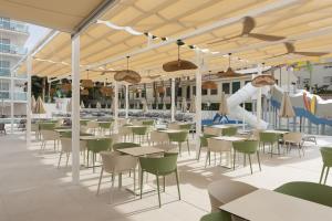 an outdoor patio with tables and chairs and a slide at Hotel Palia Las Palomas in Torremolinos