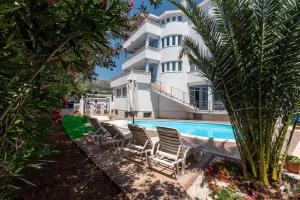 a large white building with chairs and a swimming pool at Villa Ani in Trogir